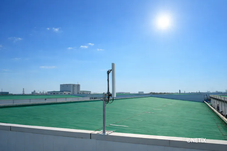 푸른 하늘 아래 건물 옥상 난간에 깔끔하게 설치된 네틱스 장거리 무선 통신 안테나 전경